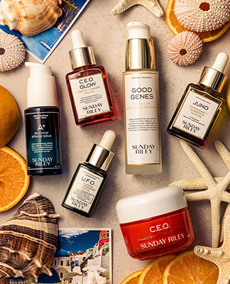 An assortment of beauty products displayed next to seashells, oranges, and photographs. The Beauty Shop. Shop Now.